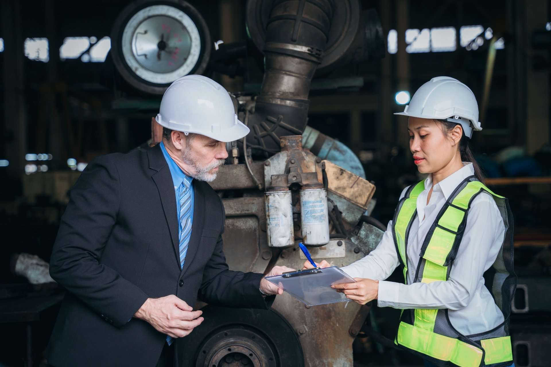 Female and male engineers reviewing plans at heavy machinery site