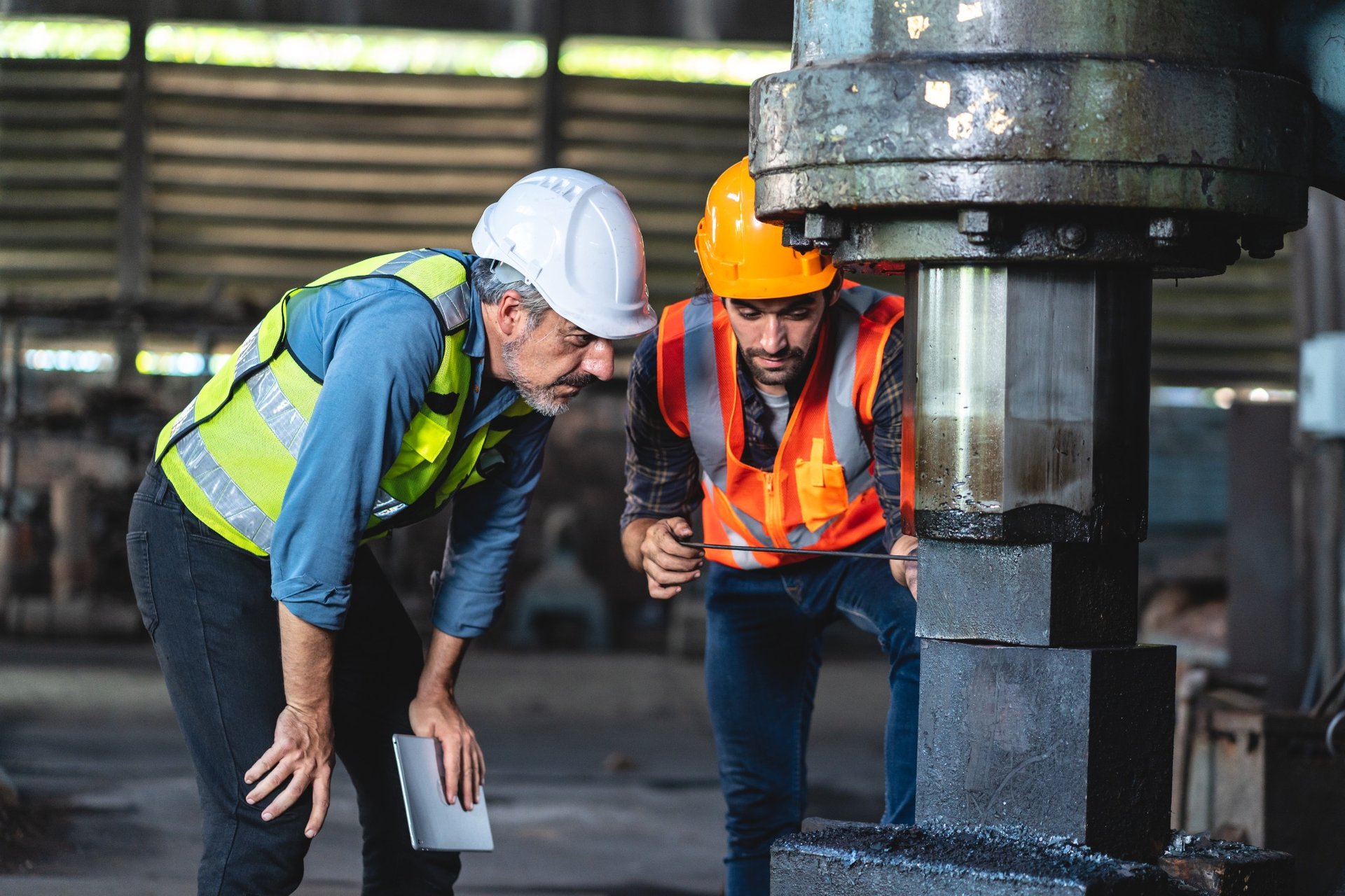 Technicians inspecting hydraulic press in safety gear
