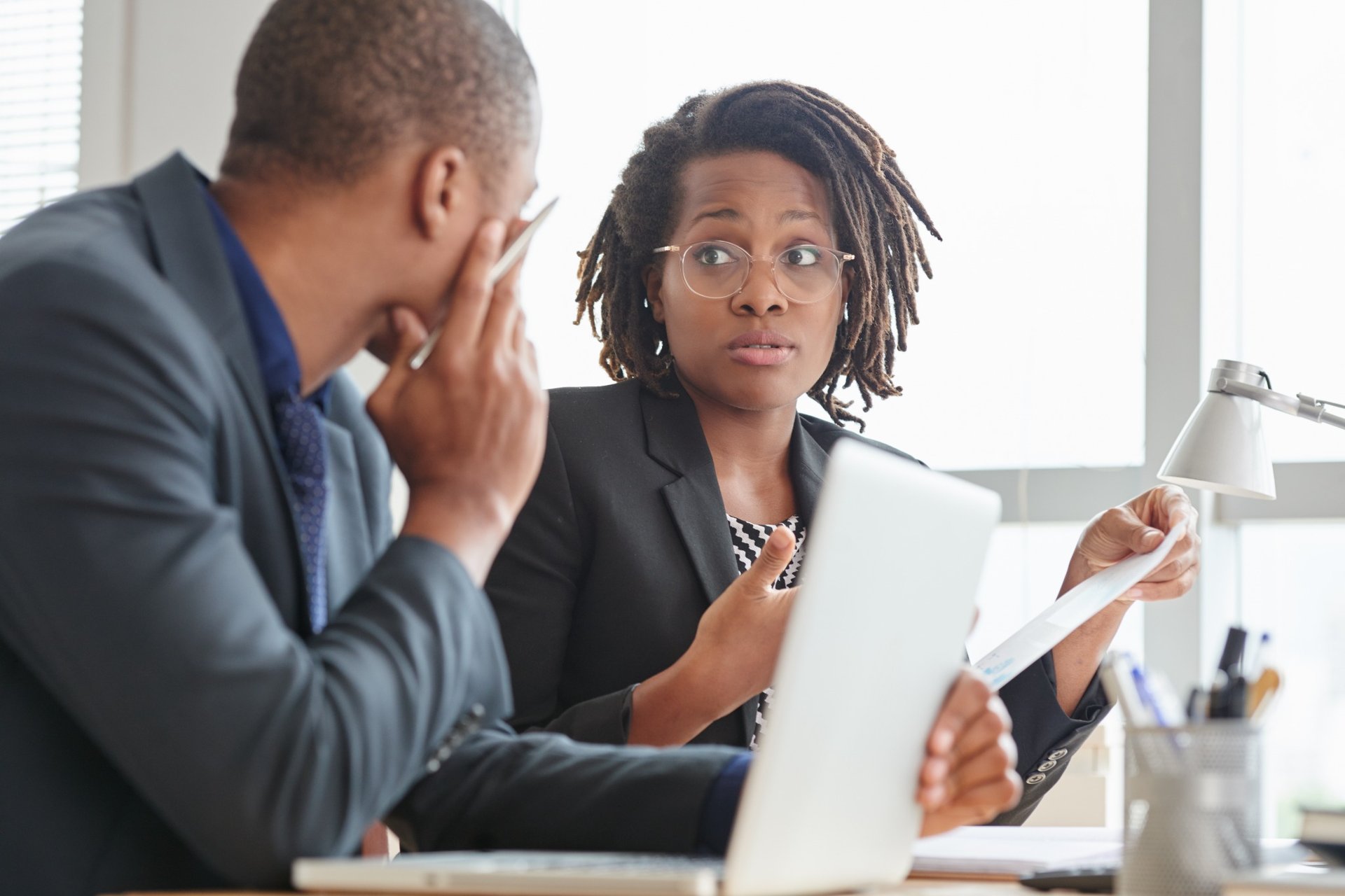 Two professionals in business attire discussing legal paperwork
